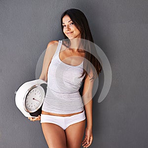 Healthy confidence. Shot of a beautiful and healthy young woman holding a scale.