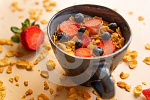 Healthy corn flakes breakfast bowl on wooden table with corn flakes, strawberries and blueberries and fruit with natural light