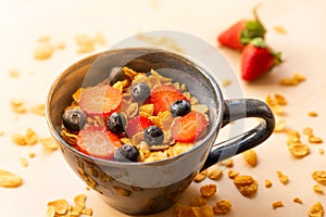 Healthy corn flakes breakfast bowl on wooden table with corn flakes, strawberries and blueberries and fruit with natural light