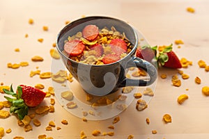 Healthy corn flakes breakfast bowl on wooden table with corn flakes, strawberries and fruit with natural light