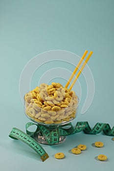 healthy corn flakes for breakfast in the form of yellow rings in a transparent glass on a bright yellow background