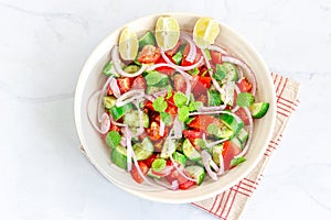 Healthy Cucumber Tomato Salad in a Bowl with Lemon, Mint, Onion and Pepper. Top View Flat Lay Horizontal Photo.
