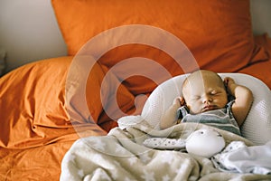 Healthy daytime sleep for the newborn. The baby is sleeping in the orthopedic Baby Cocoon on the bed
