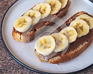 Healthy and delicious snack with peanut butter sandwiches and banana slices on a round plate, close-up