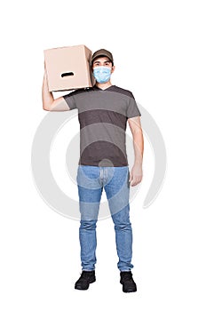 Healthy delivery man, full length portrait, wearing face mask as COVID-19 prevention measure, carrying a cardboard parcel box,