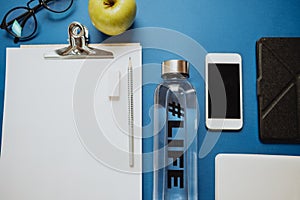 Healthy desktop: notebook, pencils, water, apple, phone, glasses