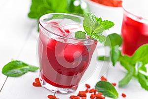 Healthy detox drink with goji berries infused in water with ice, cold refreshing beverage close-up