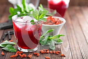 Healthy detox drink with goji berries infused in water with ice, cold refreshing beverage close-up