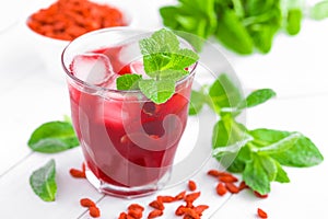 Healthy detox drink with goji berries infused in water with ice, cold refreshing beverage close-up