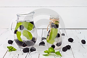 Healthy detox flavored water with blackberry and mint. Cold refreshing berry drink with ice on dark wooden table. Copy space backg