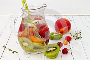 Healthy detox fruit infused flavored water. Summer refreshing homemade cocktail with fruits, thyme on wooden table. Clean eating