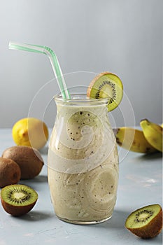 Healthy detox smoothie kiwi, banana, lemon in glass jar on light blue background with fresh ingredients, Diet and weight loss