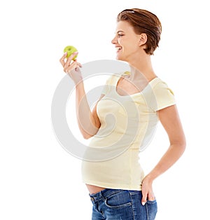 Healthy diet for the baby. A pregnant woman looking at a crunchy green apple while isolated on a white background.