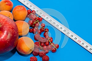 Healthy diet composition, tape measure, raspberries, apricots, apple and red currants