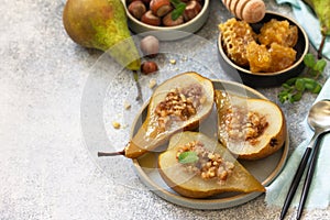 Healthy diet dessert. Baked pears with hazelnuts, honey and granola on a slate