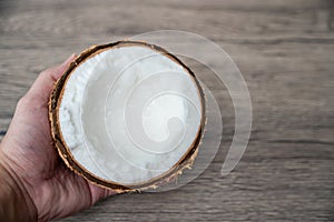 Healthy and diet: Hand holding half of coconut on a wooden background