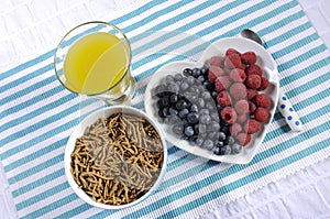 Healthy diet high dietary fiber breakfast with bowl of bran cereal and berries with pineapple juice - aerial