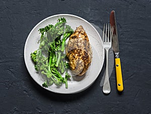 Healthy diet lunch - baked chicken breast and boiled broccoli cabbage on a dark background, top view