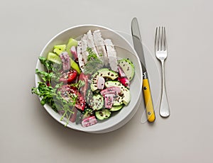 Healthy diet lunch - boiled chicken and fresh vegetable salad with seasonal vegetables on a gray background, top view