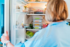Healthy diet plan for weight loss, daily ready meal menu. Woman open fridge with lunch boxes cooked in advance and ready