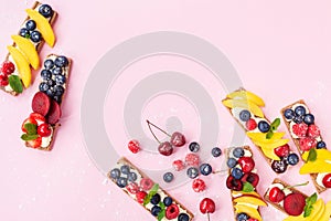 Healthy and diet snack or dessert from sandwiches with creamy cheese and summer berry fruits on pink trendy background top view.