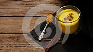 Healthy drink with milk, turmeric, cinnamon, pepper, cloves. Traditional Indian drink on a dark wooden background