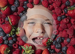 Healthy eating. Child face with berry frame, close up. Berries mix blueberry, raspberry, strawberry, blackberry