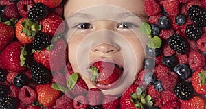 Healthy eating for children. Berries with kids face close-up. Top view of child face with berri. Berry set near kids