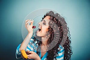 Healthy eating concept. Curly woman holding enjoying cherry in o