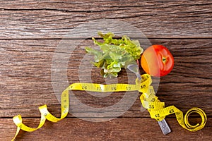 Healthy eating concept. Fork and vegetable with measure tape and fresh tomato on wooden desk. Top view and Copy space