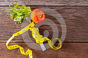 Healthy eating concept. Fork and vegetable with measure tape and fresh tomato on wooden desk. Top view and Copy space