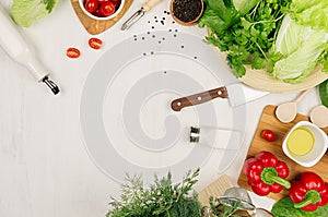 Healthy eating concept - fresh raw green salad, cherry tomatoes, paprika, spinach, cabbage and olive oil on white wood board, top