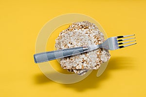 Healthy eating. Crispy bread made from oats, wheat, flax and sesame seeds in a stack and a fork on it on a yellow background.
