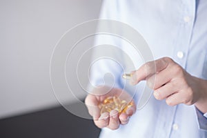 Healthy eating and diet nutrition concepts. vitamin and supplement. beautiful young woman holding yellow fish oil pill. female.