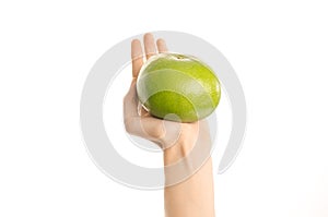 Healthy eating and diet Topic: Human hand holding a green sweetie isolated on a white background in the studio, first-person view