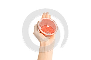 Healthy eating and diet Topic: Human hand holding a half of grapefruit isolated on a white background in the studio, first-person