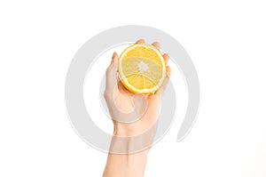 Healthy eating and diet Topic: Human hand holding a half of orange isolated on a white background in the studio, first-person view