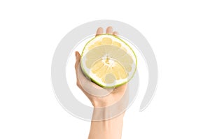 Healthy eating and diet Topic: Human hand holding a half sweetie isolated on white background in the studio, first-person view