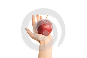 Healthy eating and diet topic: human hand holding a red apple isolated on a white background in the studio, first-person view