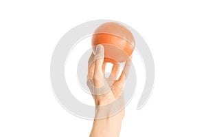 Healthy eating and diet topic: human hand holding a red grapefruit isolated on a white background in the studio, first-person view