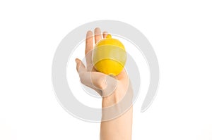 Healthy eating and diet Topic: Human hand holding yellow lemon isolated on a white background in the studio, first-person view