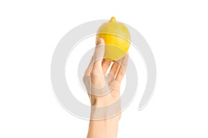 Healthy eating and diet Topic: Human hand holding yellow lemon isolated on a white background in the studio, first-person view