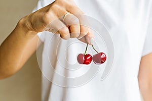 Healthy eating, dieting, vegetarian food and people concept- closeup of woman hand holding fresh berries cherry wearing white