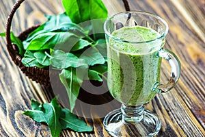 Healthy eating, drinks and diet concept. Beautiful appetizer green smoothie or spinach juice in glass jar with fresh leaves on woo