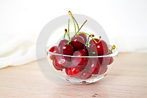 Cherries in glass dish. Cherry on wood and white background. - healthy eating and food concept