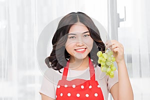 healthy eating, food, fruits, diet and people concept - happy woman eating grapes at home