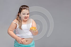 Healthy eating, glutton, bad nutritional habits, overeating, fast food, overweight. baby girl with excess weight keeps the