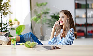 Healthy eating. happy young girl eating salad with tablet pc in morning in kitchen