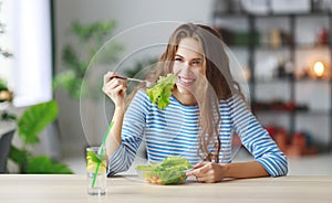 Healthy eating. happy young girl eating salad in the morning in kitchen