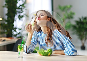 Healthy eating. happy young girl eating salad in morning in kitchen